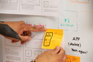 A person holding a paper with a sticky note that reads 'UX Flow and Design Notes