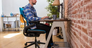 A man sitting on a chair, working remotely, with proper ergonomic support for comfort and productivity.